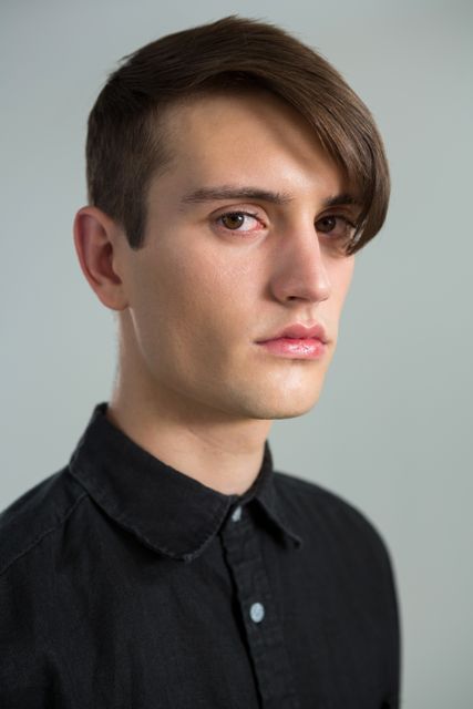 Androgynous man looking at camera against grey background