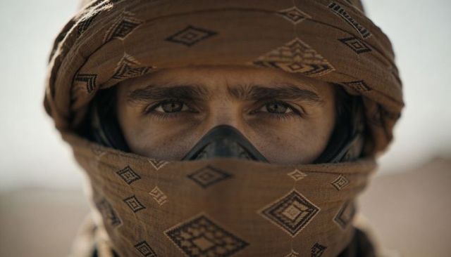 Desert rider wearing patterned shemagh and protective goggles close-up portrait