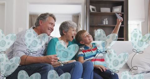 Joyful Grandparents and Grandson Taking Selfie at Home with Heart Balloons