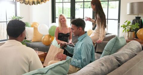 Friends Celebrating Birthday in Sunny Living Room with Gifts and Balloons