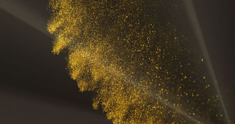 Glowing gold glitter particles on dark background