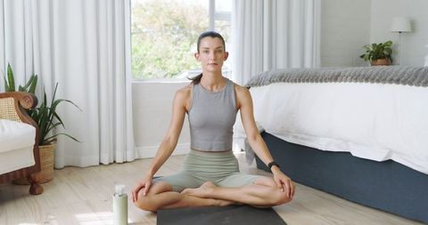 Woman Practicing Meditation on Yoga Mat in Bright Bedroom
