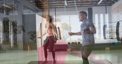 Energetic duo skipping rope in modern gym studio