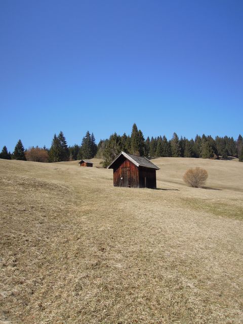 Barn on grassy hill with clear blue sky in rural countryside. Great for stories of solitude, rustic charm, rural life, or scenic backgrounds. Useful for travel brochures, nature-focused blogs, or farm and outdoor lifestyle themes.