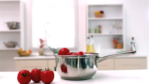 Fresh Tomatoes Falling into Steel Pot in Modern Kitchen