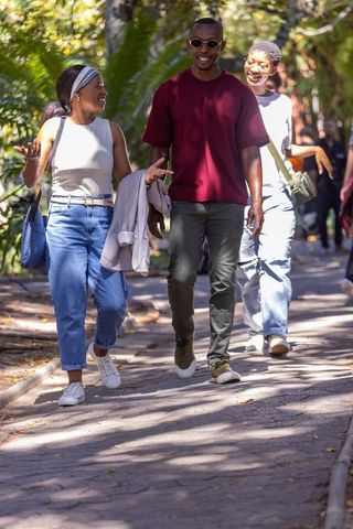 African american friends walking through sunlit tree-lined park path urban lifestyle