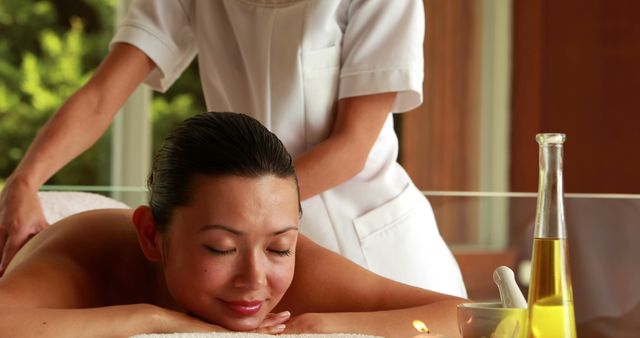 Woman receiving relaxing aromatherapy massage treatment in luxurious spa. Ideal for wellness publications, spa advertisement materials, self-care blogs, and health and wellness websites.