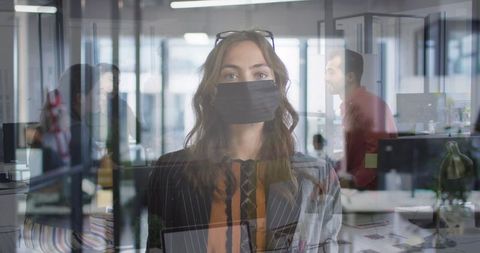 Businesswoman in mask in office with colleagues during pandemic