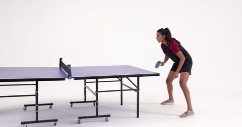 Woman practicing table tennis in studio setting