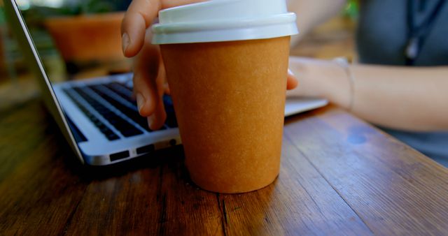 Person Working on Laptop with Coffee To-Go on Wooden Table - Download Free Stock Images Pikwizard.com