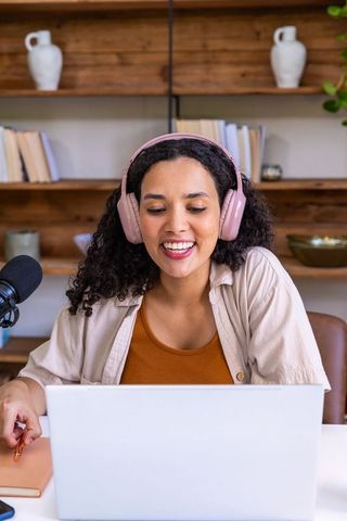 African american woman hosting podcast from home studio wearing pink headphones