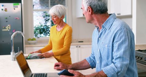 Senior Couple Multitasking in Modern Kitchen Environment