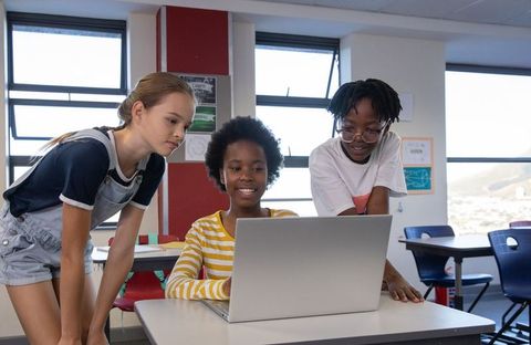 Diverse Children Collaborating on Laptop in Classroom Setting