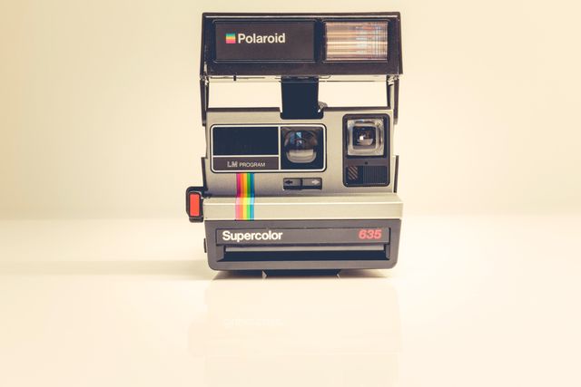 Classic Polaroid camera on beige background. Suitable for themes related to retro photography, nostalgic memories, vintage equipment, and instant photos.