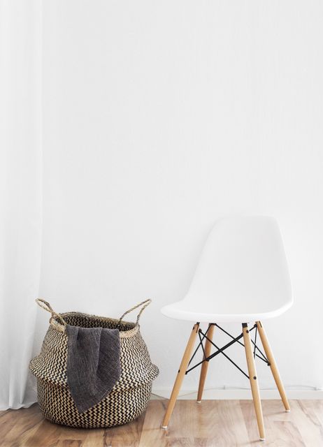 View of modern chair and laundry basket against white wall. Modern home decoration and interior concept
