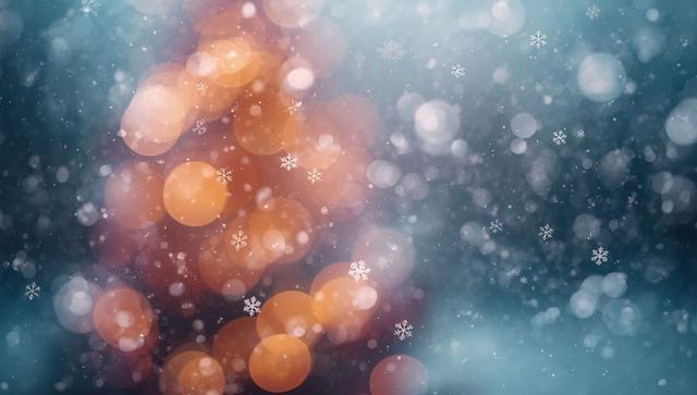 Glowing orange bokeh with falling snowflakes creating winter holiday ambience and warmth