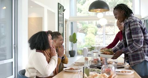Friends Serving Roasted Platter Around Bright Modern Dining Table During Celebration