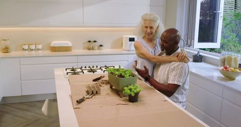 Senior Couple Embracing While Gardening Indoors