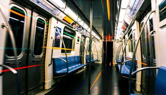 Empty subway carriage interior with motion blur, blue seats, reflective handrails, nighttime