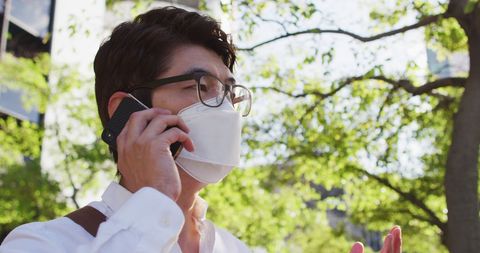 Asian Man in Mask Talking on Smartphone Outdoors - Download Free Stock Images Pikwizard.com