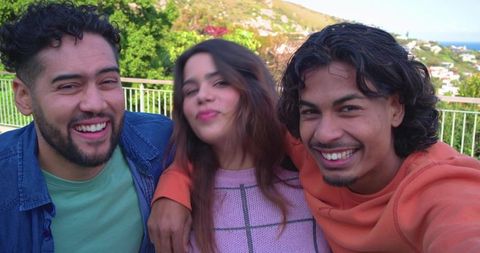 Friends taking selfie on coastal balcony smiling and laughing on sunny terrace