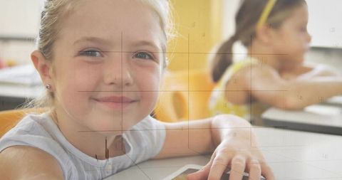 Smiling Young Girl Holding Tablet in Classroom With Friend Nearby