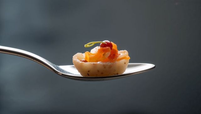 Smoked salmon tartlet balancing on spoon closeup gourmet canape with microgreens