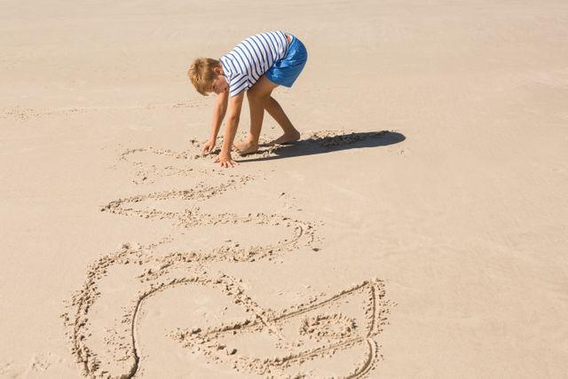 Boy drawing in sand at beach, enjoying summer vacation. Perfect for themes related to childhood, outdoor activities, summer fun, and family vacations. Ideal for use in travel brochures, educational materials, and advertisements promoting beach destinations.