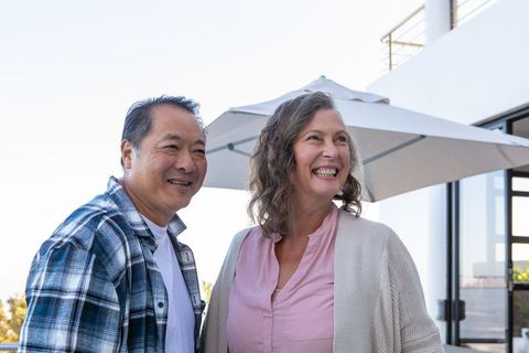 Happy Senior Couple Enjoying Time by Modern Home Balcony