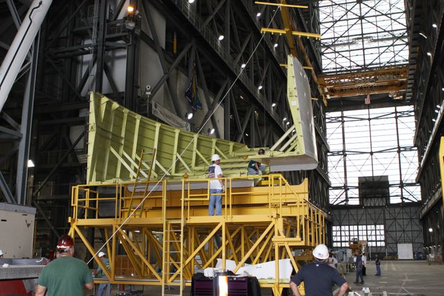 Technicians inside Kennedy Space Center's Vehicle Assembly Building prepare Endeavour's right side tail cone. This tail cone protection is essential for transporting the shuttle to the California Science Center. Great for articles or presentations on NASA's space shuttle history, engineering processes, or space exploration technology.
