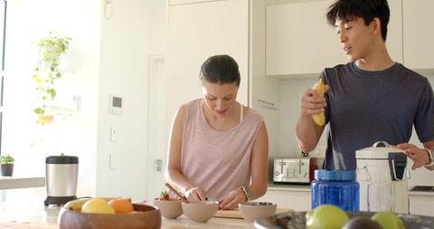 Couple preparing fresh fruit bowls together on bright modern kitchen island
