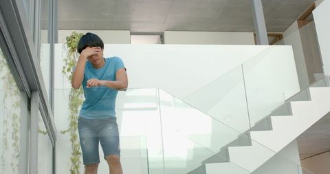 Tired Asian Student Rubbing Eyes on Staircase Slow Motion