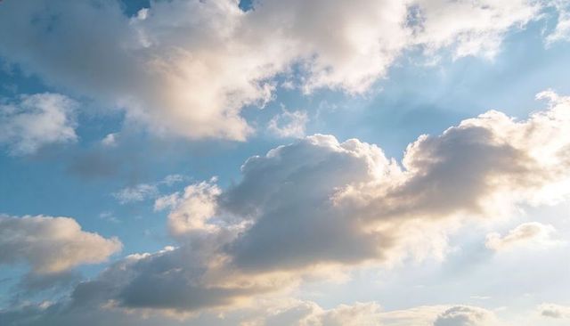 Sunlit cumulus clouds drifting across blue sky with rim lighting and soft golden glow