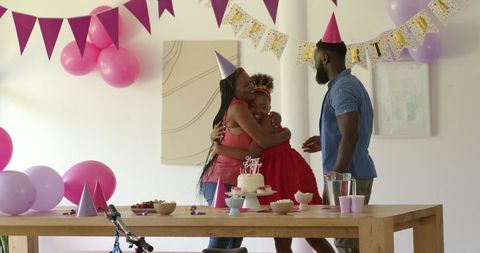 Family celebrating birthday at home with party hats and joyful embrace