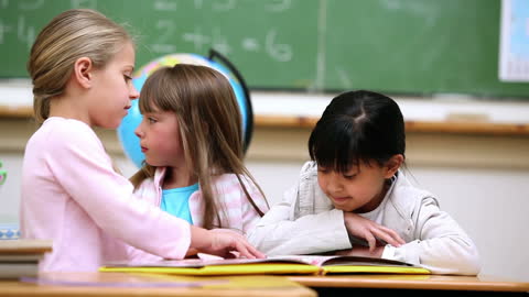 Children Collaborating in Classroom with Open Book