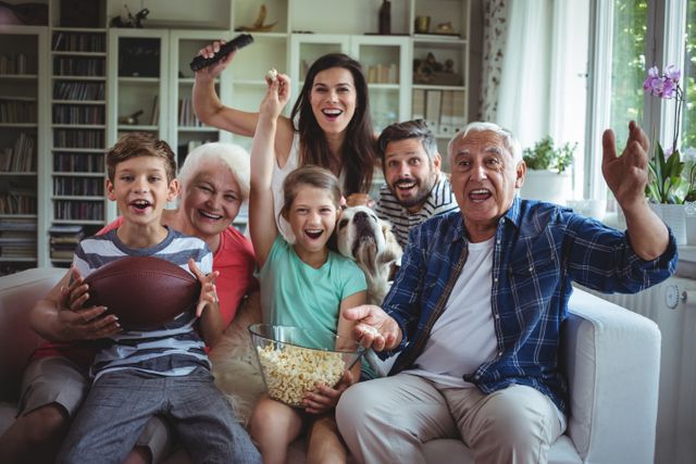 Happy multi-generation family watching soccer match on television in living room at home