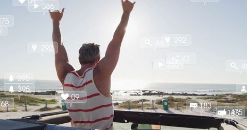 Joyful Man in Convertible Enjoying Coastal Adventure with Social Media Engagement