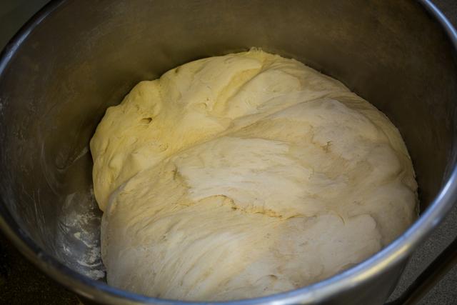 This image shows a close-up of raw dough in a metal bowl, ideal for illustrating baking and cooking concepts. It can be used in food blogs, recipe websites, cooking tutorials, and advertisements for baking products.