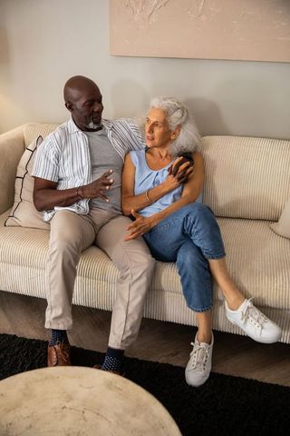 Senior Mixed-Race Couple Relaxing on Sofa Sharing Comfortable Moment