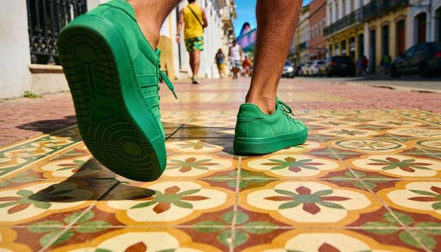 Stepping green sneakers across vibrant mosaic tiles on sunny urban street