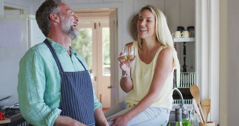 Joyful Mature Couple Cooking and Relaxing with Wine at Home