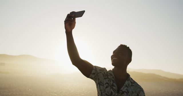 Happy african american man smiling and doing selfie in sunset. Summer, relaxation, vacation, happy time, communication.