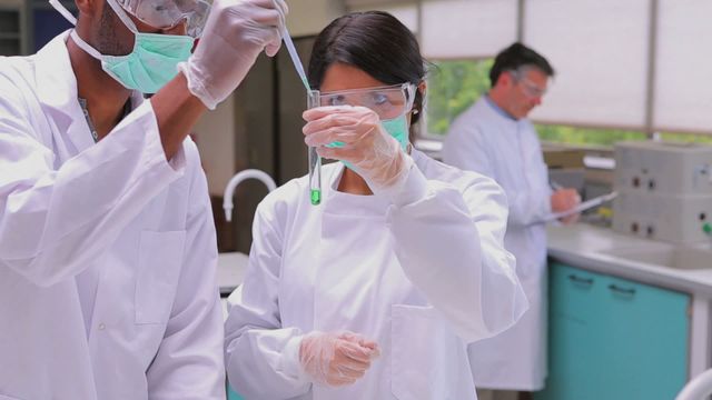 Two chemists experimenting with the green and red liquid in testtubes in the laboratory