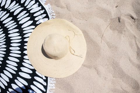 Straw Hat and Beach Towel on Sandy Beach
