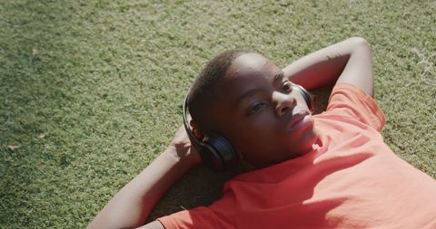 Boy Relaxing Outdoors Listening to Music on Lawn