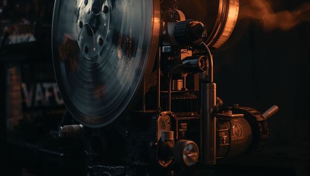 Spinning vintage film projector reel and motor close-up with warm cinematic glow