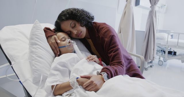 Sad biracial mother with daughter wearing oxygen mask in hospital bed. Medicine, healthcare, family and hospital, unaltered.