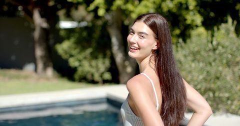 Teenage Girl Smiling Near Poolside in Sunlit Outdoor Setting