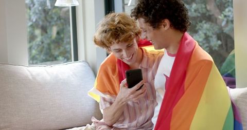 Happy Gay Couple with Rainbow Flag Relaxing at Home