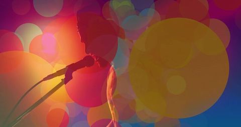 Male performer singing on stage with vibrant bokeh lights